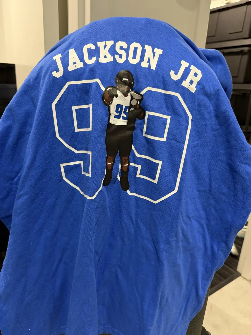 A royal blue Jackson Jr 99 tee draped over a chair