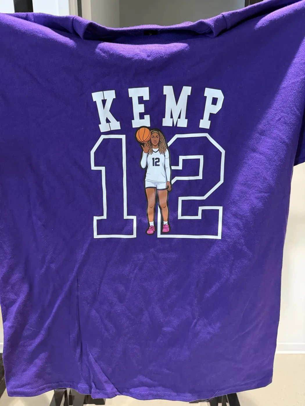 A purple Kemp 12 basketball tee held up