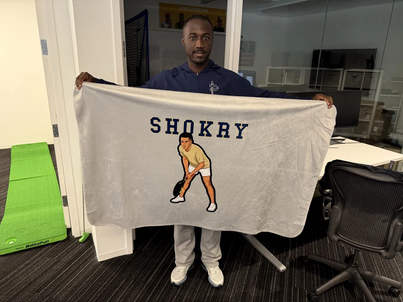 A grey Shokry blanket held up wide in an office