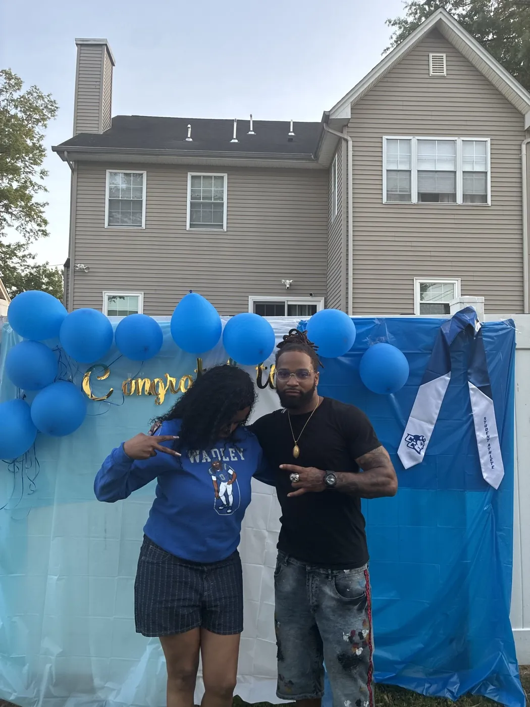 A fan in a Donovan Wadley hoodie poses with the athlete at a backyard graduation party